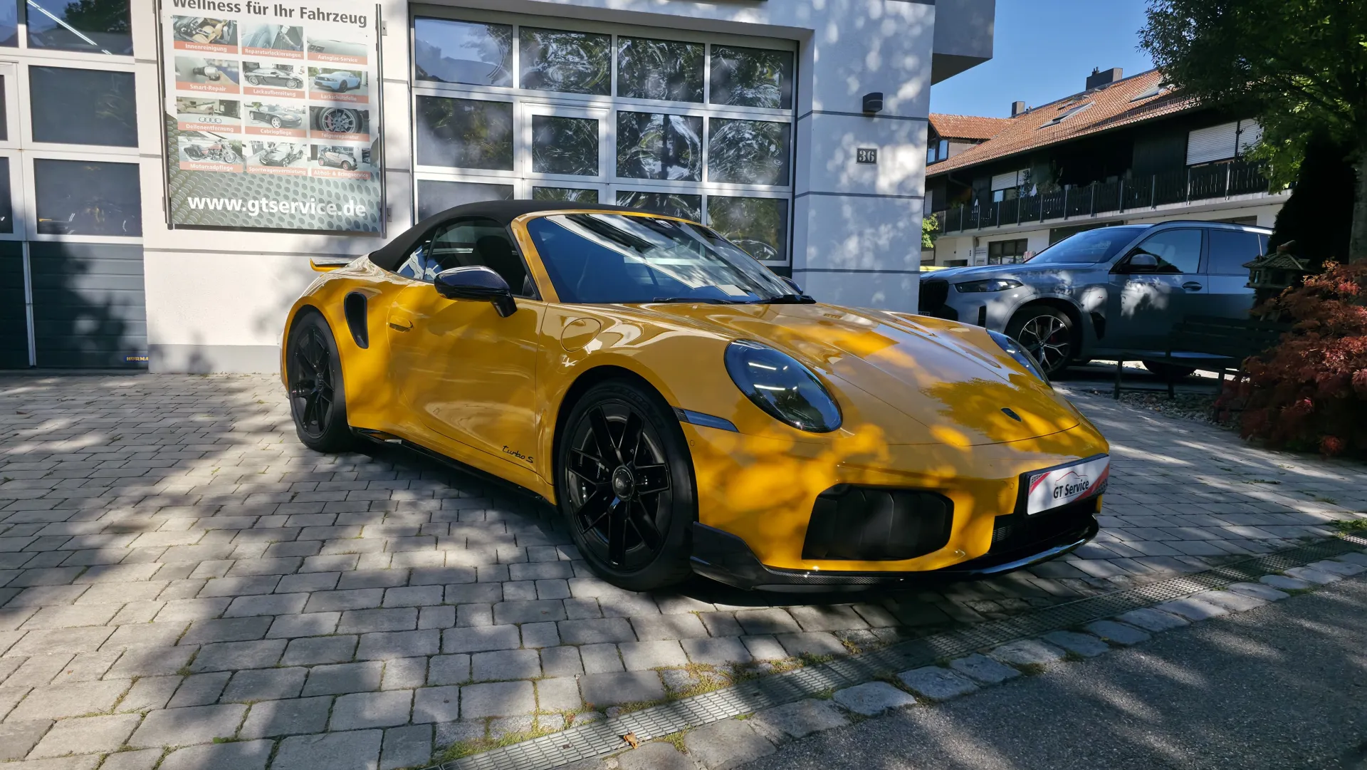 Gelber Porsche 911 Turbo S Cabriolet nach der Komplettaufbereitung vor dem GT Service Studio in Eichenau bei München